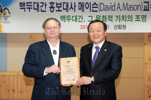 David Mason (left) holds the plaque of appointment as the Baekdu-daegan goodwill ambassador with Forestry Minister Chung Kwang-soo in the Korea Forest Service in Daejeon last Wednesday.  Yonhap News