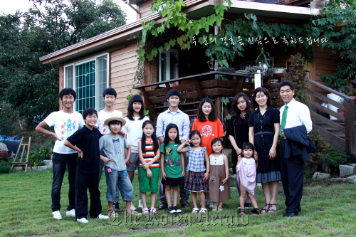 The family of 15 pose for a family photo in front of their house in Gumi.