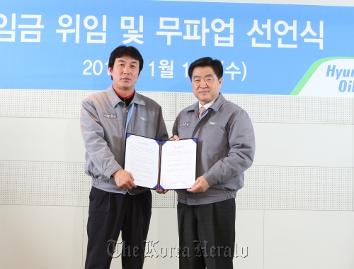 Hyundai Oilbank Co. CEO Kwon Oh-gap (right) receives power of attorney from labor union head Kim Tae-kyeong in Seoul on Wednesday. The firm’s union voluntarily waived their right to be involved in a wage negotiation this year.   Hyundai Oilbank Co
Hyundai Oilbank Co. CEO Kwon Oh-gap (right) receives power of attorney from labor union head Kim Tae-kyeong in Seoul on Wednesday. The firm’s union voluntarily waived their right to be involved in a wage negotiation this year.   Hyundai Oilbank Co