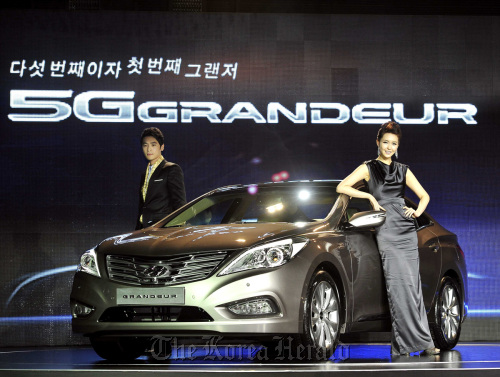 Models pose with the latest version of Hyundai Motor Co.’s large sedan Grandeur launched on the local market Thursday. The fifth generation Grandeur is available with 3- or 2.4-liter gasoline direct injection engines.  Hyundai Motor Co.
