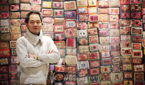 Traditional hanbok designer Kim Young-seok poses in front of a mosaic wall stacked with traditional pillows of his design at his boutique. Park Hae-mook/The Korea Herald