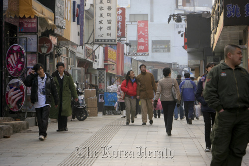 People walk along a shopping street in Beijing.  Bloomberg
