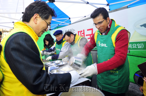 S-Oil CEO Ahmed A. Subey (right) helps out in an event to give free tteokguk, traditional Korean rice cake soup typically eaten on Lunar New Year, to homeless people in a charity event in Seoul on Thursday.  S-Oil