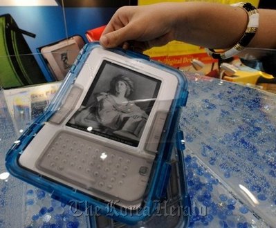 An Amazon Kindle, protected by a special waterproof case, is immersed in water at a consumer electronics show.  AFP-Yonhap News