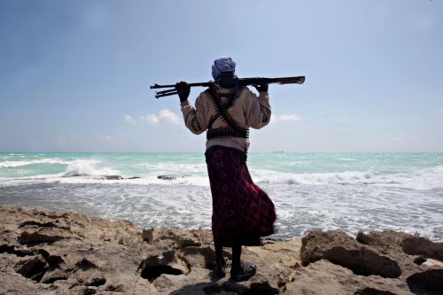 A file photo taken on January 7, 2010 shows an armed Somali pirate along the coastline while the Greek cargo ship, MV Filitsa, is seen anchored just off the shores of Hobyo, northeastern Somalia, where its being held by pirates. On the 20th anniversary of president Mohamed Siad Barre's ouster that triggered Somalia's descent into chaos and one of Africa's longest civil wars, prospects for peace remain slim, analysts said. The Horn of Africa country is now best known to the outside world for being the place that inspired the Hollywood war movie "Black Hawk Down" and the reason the term "failed state" was coined. (AFP )