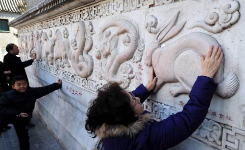 <YONHAP PHOTO-0923> TO GO WITH Lifestyle-China-tradition-society-Lunar,FOCUS by Sebastien Blanc This photo taken on January 30, 2011 shows a woman rubbing her hands for good luck across a bas relief sculpture of a rabbit along a wall of bas relief sculptures depicting the 12 animals of the Chinese zodiac at the White Cloud Temple in Beijing ahead of arrival of the "Year of the Rabbit" on February 3. In stews, as pets or adorning shop windows, rabbits have become hugely popular in China, where even brokerages hope their unifying influence will help bring good fortune in the Lunar New Year. The Taoist White Cloud temple, known locally as Baiyuguan, is one of the oldest in northern China dating back to the mid-8th century. AFP PHOTO/Frederic J. BROWN /2011-01-31 12:08:56/ <저작권자 ⓒ 1980-2011 ㈜연합뉴스. 무단 전재 재배포 금지.>
A woman rubs her hands across a bas-relief sculpture of a rabbit for good luck at the White Cloud Temple in Beijing ahead of the arrival of the “Year of the Rabbit” on Feb. 3.   AFP-Yonhap News