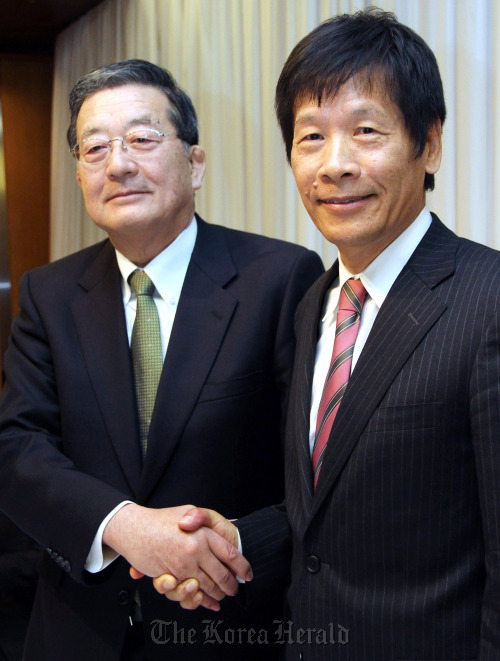 Shoji Muneoka, president of Nippon Steel Corp. (left) and Hiroshi Tomono, president of Sumitomo Metal Industries Ltd., shake hands during a news conference in Tokyo on Thursday.  Bloomberg