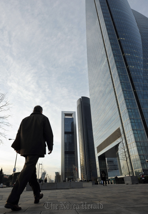 A commuter walks toward the new Cuatro Torres office buildings in Madrid.  Bloomberg