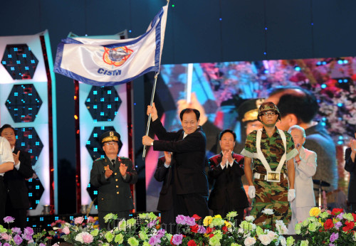 Mungyeong Mayor Shin Hyun-kook waves a flag hoping for the city’s successful bid for the CISM Military World Games 2015 during a local riverside festival last August. Mungyeong City