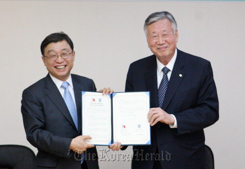 Seoul National University President Oh Yeon-cheon (left) and Booyoung Group Chairman Lee Joong-keun after Lee signed a pledge of donation for the construction of a social contribution center on the campus Wednesday.  Yonhap News