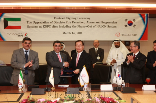 Hanwha E&C CEO Kim Hyung-chung and Kuwait National Petroleum Co.’s Asaad Ahmad Al-Saad (second from left) shake hands after signing a contract in Safat, Kuwait, Monday.  Hanwha Engineering and Construction Co.