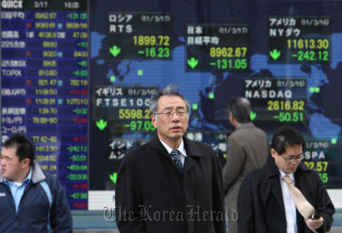 Pedestrians walk in front of an electronic stock board outside a securities firm in Tokyo.  Bloomberg