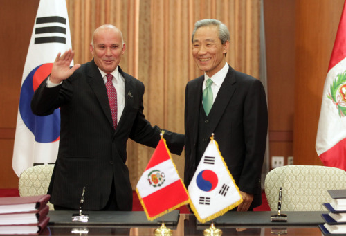<YONHAP PHOTO-2057> 한ㆍ페루 FTA 서명식 (서울=연합뉴스) 최재구 기자 = 김종훈 통상교섭본부장(오른쪽)과 에두아르도 페레이로스 페루 통상관광부장관이 21일 서울 세종로 외교부에서 한ㆍ페루 자유무역협정 서명식을 마친 후 기자들에게 인사하고 있다. 2011.3.21 jjaeck9@yna.co.kr/2011-03-21 17:04:04/ <저작권자 ⓒ 1980-2011 ㈜연합뉴스. 무단 전재 재배포 금지.>
Peruvian Trade Minister Eduardo Ferreyros (left) waves to reporters after he and his Korean counterpart Kim Jong-hoon signed a free trade agreement between the two countries in Seoul on Monday.  Yonhap News