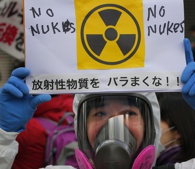 A protester in protective mask holds a placard during an anti nuclear rally in Tokyo, Sunday. (AP-Yonhap news)