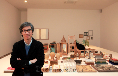 Koo Bohnchang in front of a table full of his private collection.   Kukje Gallery