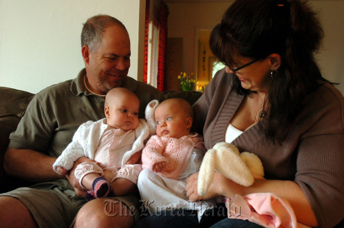 Mike Rose (left) holds daughter Sophia as Stephanie Lovell-Rose holds Sophia’s twin sister Allison at home in El Cerrito, California, March 24.  Contra Costa Times/MCT
