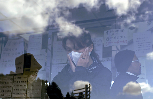 A woman reads a list which describes the dead for families
searching for missing loved ones, posted at a shelter in the earthquake-
and tsunami-destroyed town of Minamisanriku, northeastern
Japan. (AP-Yonhap News)