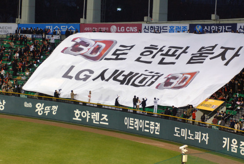 LG전자가 13일 잠실 와이즈 토토 열린 삼성과의 경기에서 이색 응원전을 펼쳐 눈길을 끌었다.  LG전자 한국마케팅본부 직원 1000여명이 경기장을 직접 찾아 ‘3D로 한판 붙자’라고 쓰인 가로와 세로 길이가 각각 32m, 15m인 초대형 플래카드를 선보였다. 이 응원은 경기장을 찾은 고객들에게  LG 시네마 3D TV의 우수성을 알리는 한편 한국마케팅 임직원들의 3D 시장 선도의지를 다지기 위해 마련됐다.  [사진제공=LG전자]