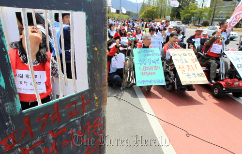 A woman locks herself in a prison-shaped cardboard box calling for the end of social discrimination against impaired people at a protest in front of South Gyeongsang provincial government in Changwon, Tuesday, ahead of the Day of Persons with Disabilities.  Yonhap News
A woman locks herself in a prison-shaped cardboard box calling for the end of social discrimination against impaired people at a protest in front of South Gyeongsang provincial government in Changwon, Tuesday, ahead of the Day of Persons with Disabilities.  Yonhap News