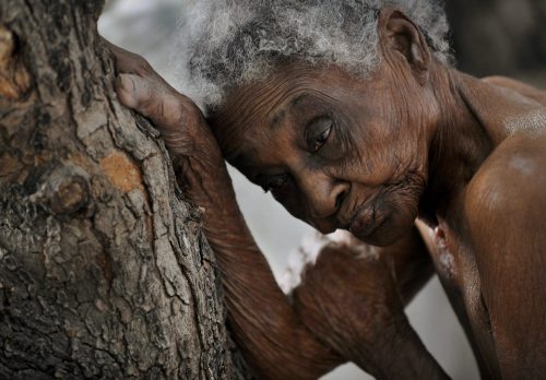 In this Jan. 2010 photo submitted by the Washington Post tilted "The Elderly" Idamise Pierre leans against a tree as she waits to bathe at the Azil Communal Home for the Aging. (AP-Yonhap News)