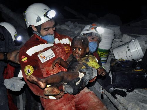 In this Jan. 2010 photo submitted by the Washington Post tilted "Rescue", a tiny baby named Reggie Claude is rescued from the rubble of his home. Disaster relief workers and family members rejoiced as Oscar Vega carried the child through the streets. (AP-Yonhap News)