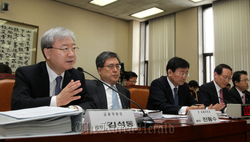 Financial Services Commission Chairman Kim Seok-dong (left) responds to a question from lawmakers at a parliamentary hearing on the closure of several savings banks Thursday.   Yonhap News