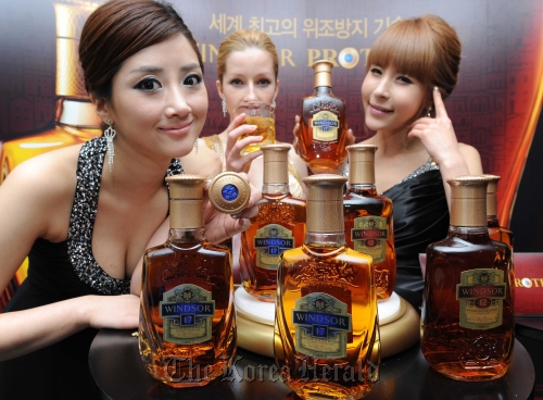 Models pose with Diageo Korea’s Windsor whiskies bottled in Windsor Protect bottles in Seoul on Tuesday. Diageo Korea