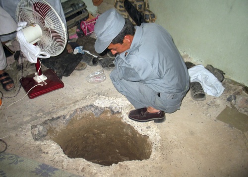 An Afghan policemen takes a look at the opening of tunnel at the main prison in Kandahar, Afghanistan which prisoners escaped through Monday, April 25, 2011. Taliban insurgents dug a more than 1,050-foot (320-meter) tunnel underground and into the main jail in Kandahar city and whisked out more than 450 prisoners, most of whom were Taliban fighters, officials and the insurgents said Monday. (AP-Yonhap News)