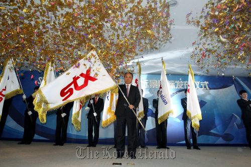 STX Group chief Kang Duk-soo waves the company’s flag at the 10th year celebrations held at the company’s plant in Dalian, China on Friday. STX Group