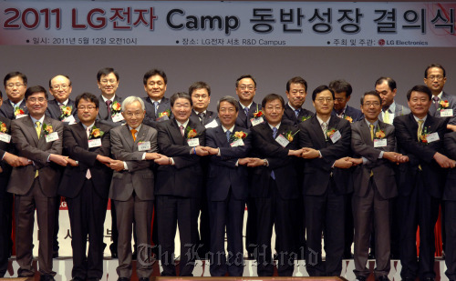 LG Electronics vice chairman Koo Bon-joon (fourth from left, front row), Chung Un-chan, head of the Presidential Commission on Shared Growth for Large and Small Companies (fifth from left, front row), and LG’s subcontractors pledge mutual growth at the company’s research and development center in southern Seoul on Thursday. LG Electronics