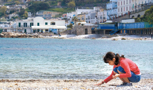 Joie, 10, looks for sea glass on a rocky beach near Marina Grande on the island of Capri, Italy.