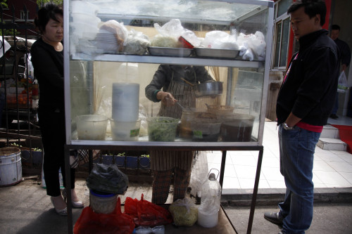 <YONHAP PHOTO-1380> In this photo taken Thursday, May 12, 2011, a roadside street vendor prepares food for customers in Beijing, China. The headlines are unrelenting: toxic bean sprouts, filthy oil, drug-tainted pork. For months, Chinese media have been churning out a queasy-making multitude of stories about the dangers lurking in the nation's dinner bowls. (AP Photo/Ng Han Guan)/2011-05-15 13:56:36/ <저작권자 ⓒ 1980-2011 ㈜연합뉴스. 무단 전재 재배포 금지.>
Street vendor prepares food for customers in Beijing.  AP-Yonhap News