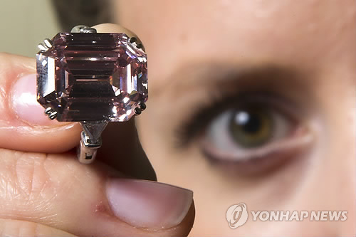 A model holds up a ring mounting a rare translucent pink diamond during a Sotheby's auction press preview in Geneva. Mounted in a ring the 10.99-carat, emerald-cut stone that is classified as "fancy intense pink" sold for a price of $10.8 million(7.6 million  Euro) during a Sotheby's auction in Geneva on May 17. (Yonhap News)