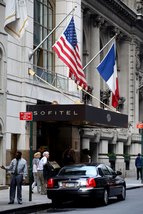The American and French flags hang over the Sofitel hotel Sunday, May 15, 2011 in New York where International Monetary Fund head Dominique Strauss-Kahn, 62, was staying Saturday and is accused of an alleged assault involving a maid. Strauss-Kahn was plucked from a first class seat on a Paris-bound Air France flight that was just about to leave the gate at John F. Kennedy International Airport about four hours after the incident, taken into police custody. (AP-Yonhap News)