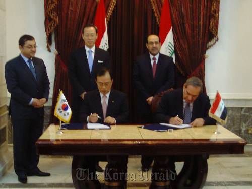 Iraqi Prime Minister Nouri al-Maliki (right, back row) looks on as Hanwha Engineering and Construction Corp. CEO Kim Hyun-chung (second from left) and Head of National Investment Commission Sami Al-Araji (second from right) sign the contract at the Prime Minister’s office in Baghdad on Wednesday.  Hanwha Engineering and Construction Corp.
