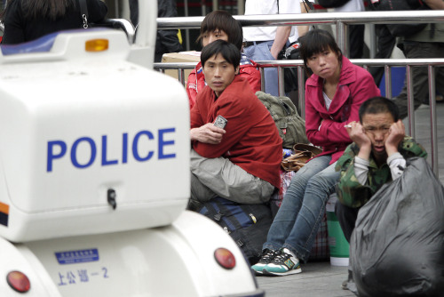 Migrant workers sit near a police electric car patrolling around Shanghai train station on Sunday, May 22, 2011 in Shanghai, China. North Korean leader Kim Jong Il, whose rare foreign trips are cloaked in secrecy, was traveling to Yangzhou, west of Shanghai Sunday, the Yonhap news agency and broadcaster YTN said, citing diplomatic sources. (AP-Yonhap News)