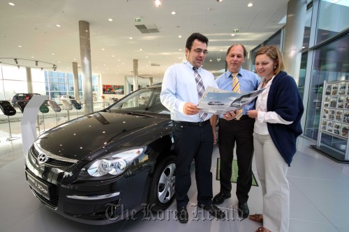 A sales employee (left) explains car specifications to customers at a Hyundai Motor dealership in Germany.     Hyundai Motor
