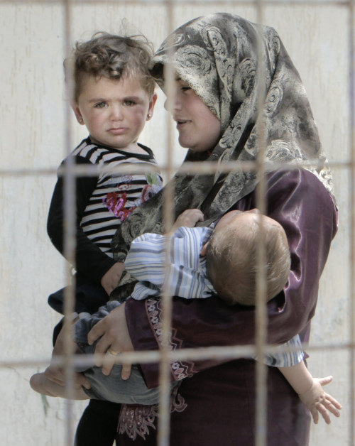 <YONHAP PHOTO-2276> A Syrian refugee woman carries two children in a camp in Yayladagi, Turkey, near the Syrian border, Sunday, June 12, 2011. According to local media the number of Syrians that fled their country seeking refuge in Turkey has gone above 5.000 on Sunday.(AP Photo/Vadim Ghirda)/2011-06-12 22:39:37/ <저작권자 ⓒ 1980-2011 ㈜연합뉴스. 무단 전재 재배포 금지.>
A Syrian refugee carries two children at a camp in Yayladagi, Turkey, near the Syrian border on Sunday.  AP-Yonhap News