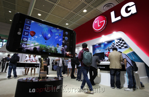 A model of LG Electronics Inc.’s newly unveiled Optimus 3-D smartphone sits on display at the entrance of the company’s booth at the World IT Show 2011 in Seoul in May.   Bloomberg