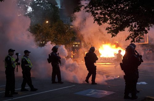 Riot police look on as two police cars burn during a riot in downtown Vancouver, British Columbia Wednesday, June 15, 2011 following the Vancouver Canucks 4-0 loss to the Boston Bruins in game 7 of the Stanley Cup hockey final.(AP-Yonhap News)