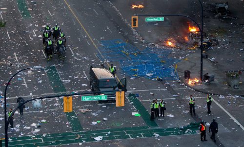 Police officers stand amongst debris after rioters moved through the area following the Vancouver Canucks being defeated by the Boston Bruins in the NHL Stanley Cup Final. (AP-Yonhap News)