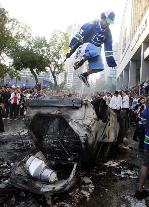Canucks fans jump onto a destroyed car during a riot in Vancouver, Canada, June 15, 2011. (Xinhua-Yonhap News)