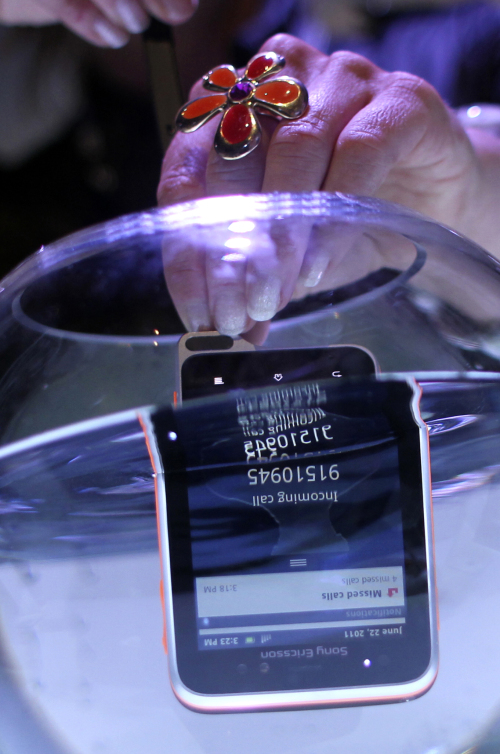 <YONHAP PHOTO-2446> A staff member of Sony Ericsson submerges the newly-launched Xperia Active phone into a bowl of water as it receives an incoming call to show off its underwater capability on Wednesday, June 22, 2011 in Singapore. Mobile phone maker Sony Ericsson has unveiled two new Android models in a bid to grab more of the burgeoning smartphone market. Chief Marketing Officer Matthew Lang announced Wednesday in Singapore that the company plans to launch the Xperia ray and Xperia active models during the third quarter. (AP Photo/Wong Maye-E)/2011-06-22 18:49:49/ <저작권자 ⓒ 1980-2011 ㈜연합뉴스. 무단 전재 재배포 금지.>
A staff member submerges the Xperia Active in a bowl of water, to show its underwater capability in Singapore on Wednesday.   AP-Yonhap News