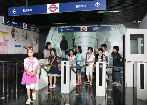 Students use a railway station with signs written in English at Busan Global Village.