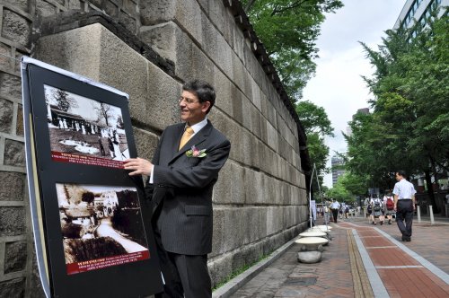 German Ambassador Hans-Ulrich Seidt stands in front of the remnants of a bridge, which connected the former German Legation with Deoksu Palace, while discussing a picture taken in what could have been the last German diplomatic garden party before the annexation of Korea. (Yoav Cerralbo/The Korea Herald)