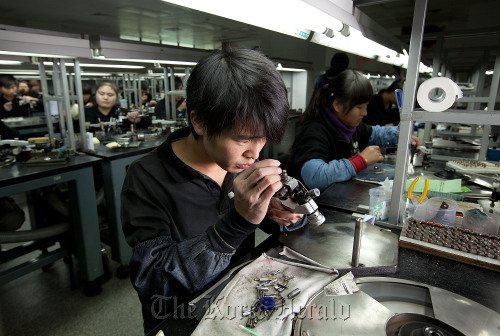 Workers polish diamonds in one of two rooms of polishing benches at the Guangzhou Mickey Weinstock & Co.  Bloomberg
