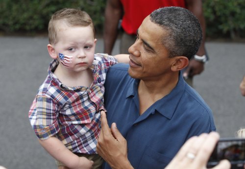 President Barack Obama picks up a child as he greets military families at an Independence Day celebration on the South Lawn of the White House in Washington, Monday, July 4, 2011. (AP-Yonhap News)