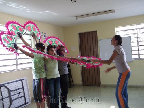 Mana Eugenia Olsen Agular (right) helps young Mexican women practice a Korean fan dance at the Merida Korean Language School.  Yonhap News