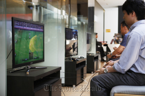 Visitors play a video game on Samsung Electronics Co.’s flat screen televisions at the company’s headquarters in Seoul.    Bloomberg