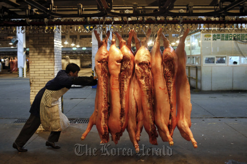 A worker moves pig carcasses at a meat wholesale and distribution center in Shanghai.  Bloomberg